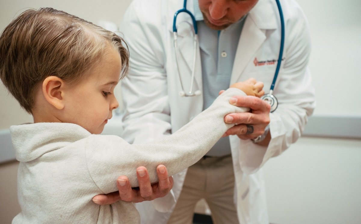 medical provider examining nurse maid elbow on toddler patient medical provider examining nurse maid elbow on toddler patient